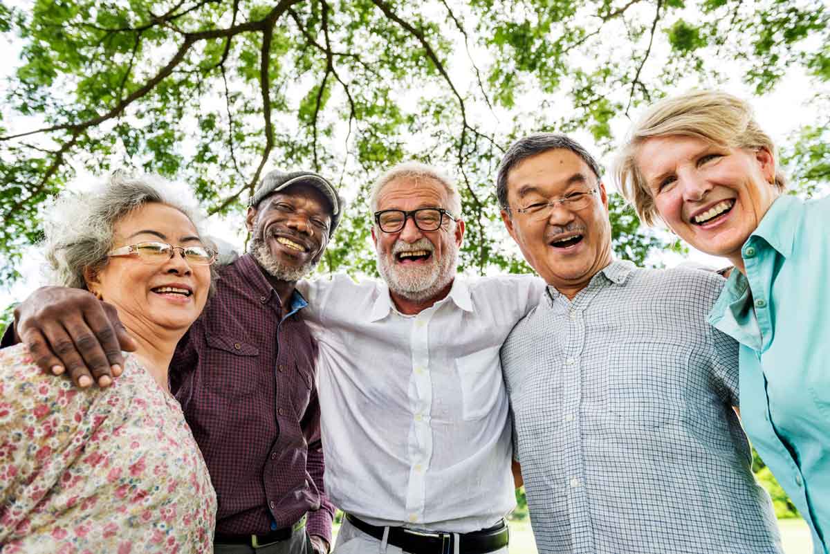 group of seniors from different cultures huddled together with arms around each others shoulders